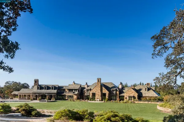 a view of a house with a big yard and large trees