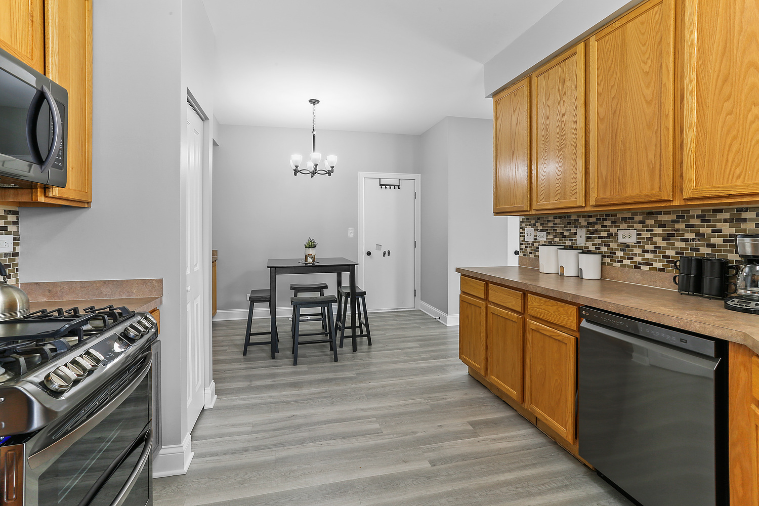 7007 Creekside Drive Plainfield, IL 60586 - Photo 7 of 21 a kitchen with stainless steel appliances a table chairs and a stove top oven