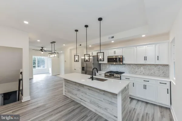 a kitchen with stainless steel appliances a stove a sink a microwave a refrigerator and cabinets