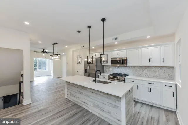 a kitchen with stainless steel appliances a stove a sink a microwave a refrigerator and cabinets