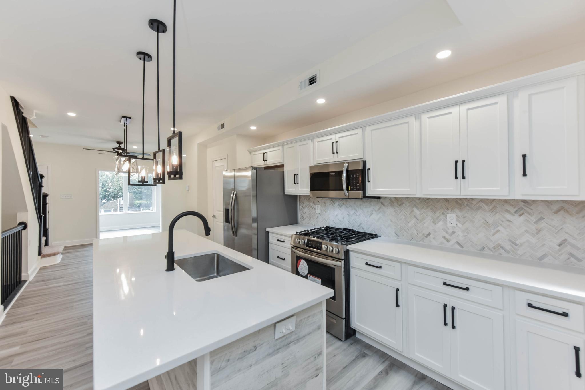 3108 Brighton Street Baltimore, MD 21216 - Photo 15 of 31 a kitchen with stainless steel appliances a stove a sink a microwave a refrigerator and cabinets