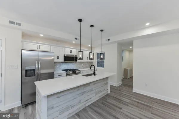 a kitchen with kitchen island a sink stainless steel appliances and cabinets