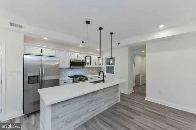 a kitchen with kitchen island a sink stainless steel appliances and cabinets
