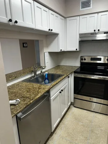 a kitchen with stainless steel appliances granite countertop a sink stove and cabinets