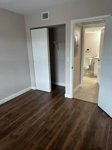 an empty room with wooden floor and a bathroom