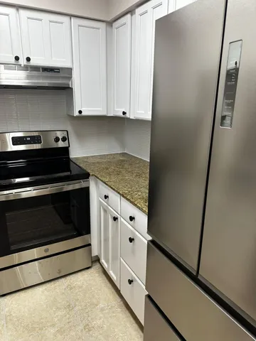 a kitchen with granite countertop white cabinets and white appliances