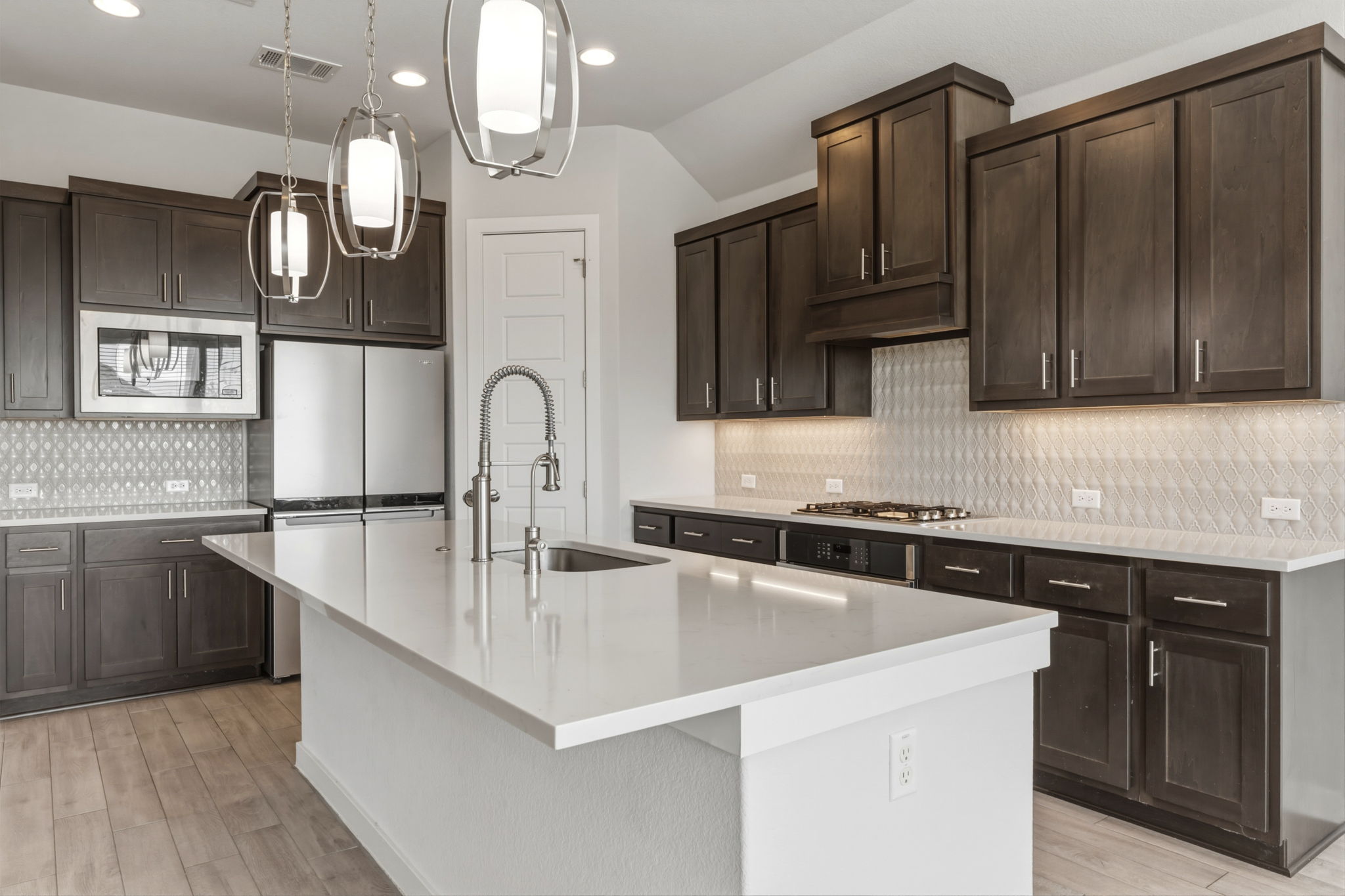 116 Tanali Trail Georgetown, TX 78628 - Photo 20 of 40 Kitchen with dark wood finish cabinets, an island with sink, pendant lighting, stainless steel appliances, and lofted ceiling
