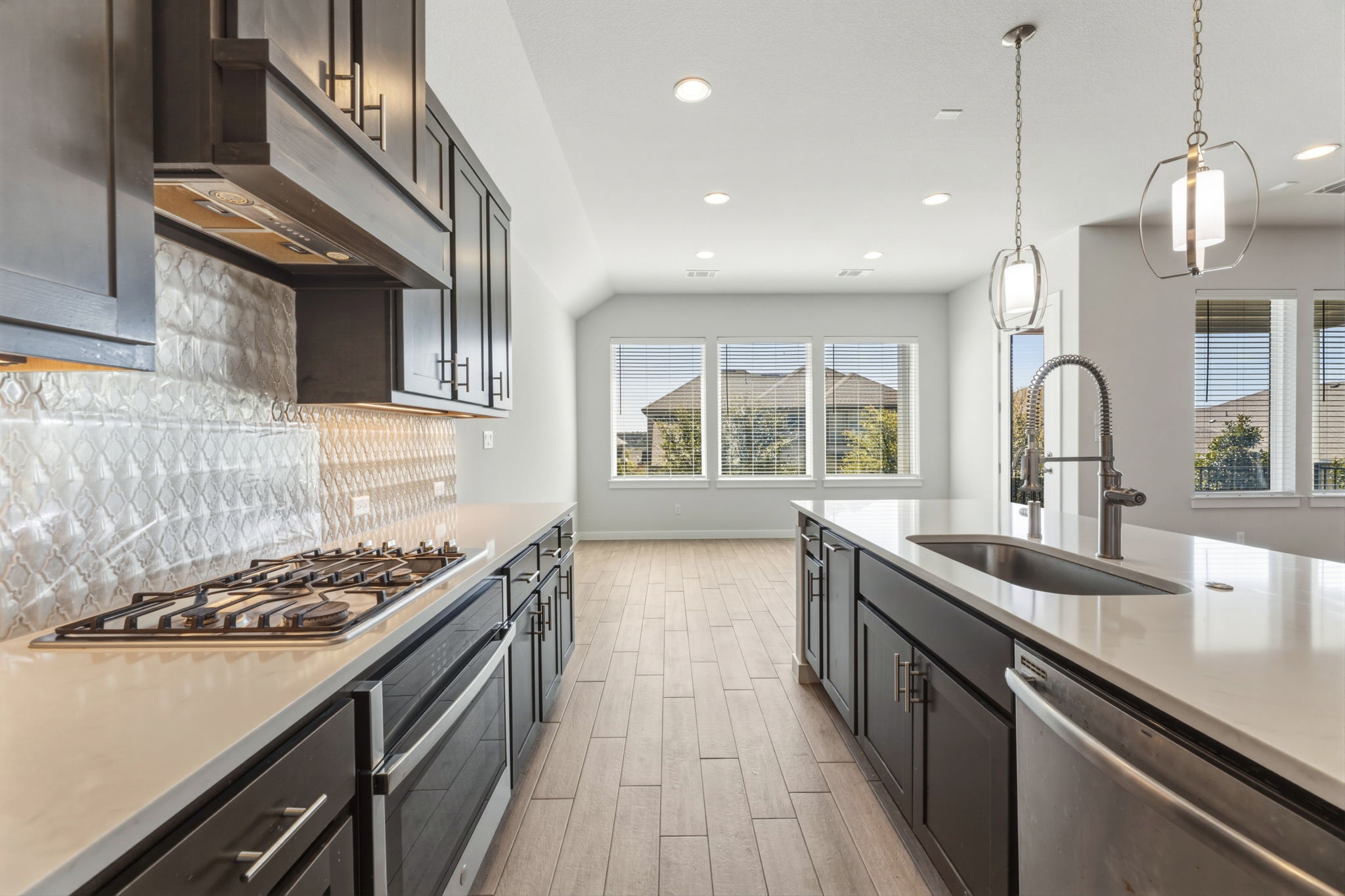 116 Tanali Trail Georgetown, TX 78628 - Photo 21 of 40 Kitchen featuring stainless steel appliances, light stone countertops, decorative backsplash, wood tiled floors, and pendant lighting