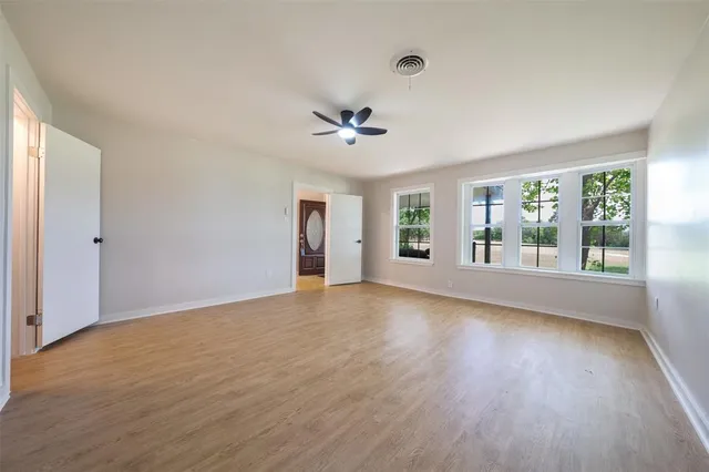 a view of an empty room with a window and wooden floor