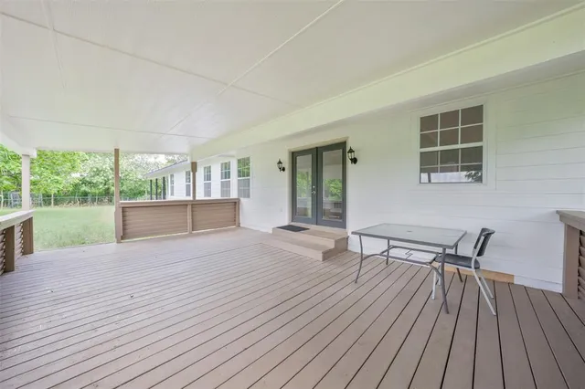 a view of a patio with table and chairs with wooden floor and fence