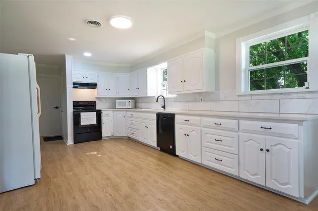 a kitchen with white cabinets and window