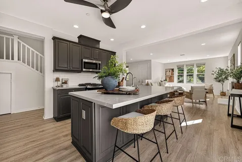 a kitchen with stainless steel appliances granite countertop a stove top oven a sink dishwasher a dining table and chairs with wooden floor