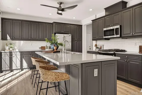a kitchen with stainless steel appliances granite countertop a sink a stove a microwave a refrigerator cabinets and chairs
