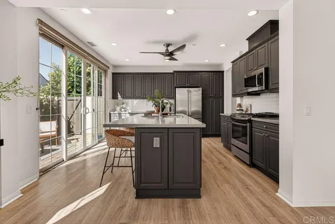 a kitchen with stainless steel appliances granite countertop a refrigerator a sink dishwasher a stove and a microwave oven with wooden floor