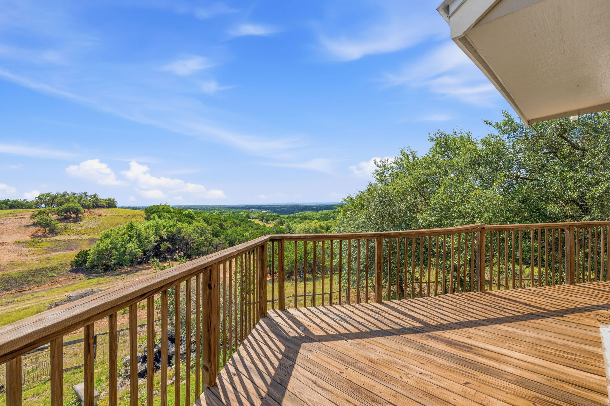 3230 West Fitzhugh Road Dripping Springs, TX 78620 - Photo 3 of 34 A spacious wooden deck provides an elevated vantage point overlooking rolling hills and verdant tree lines.