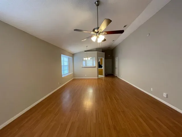 a view of an empty room with window and wooden floor