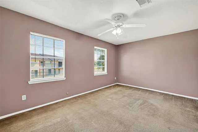 an empty room with windows and chandelier fan