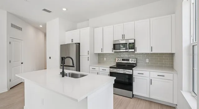 a kitchen with kitchen island a sink stainless steel appliances and cabinets