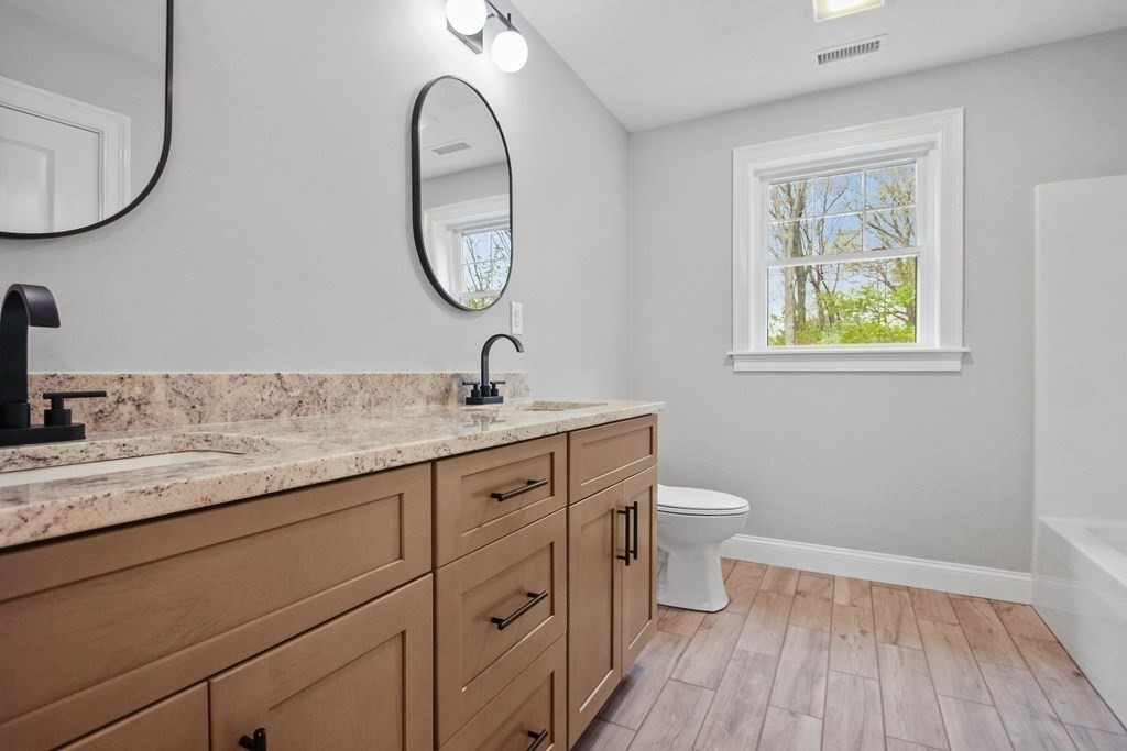 529 Chadwick Road Haverhill, MA 01835 - Photo 33 of 38 a bathroom with a granite countertop toilet a sink and a mirror