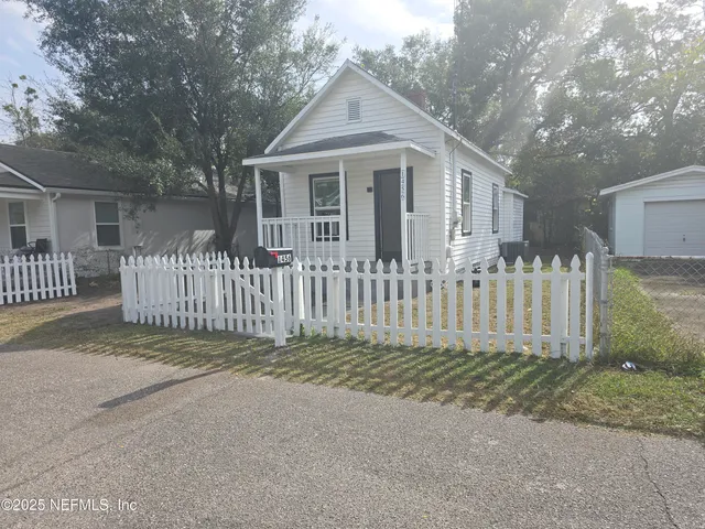 a white house that has a small yard and large trees