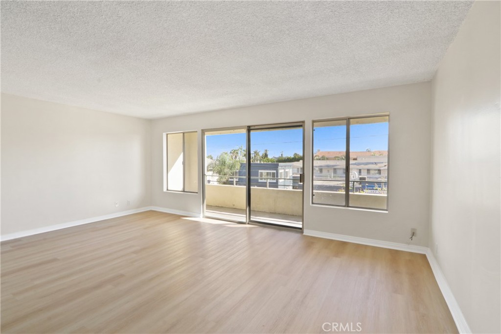 1187 East 3rd Street, Unit 215 Long Beach, CA 90802 - Photo 3 of 15 a view of an empty room with wooden floor and a window