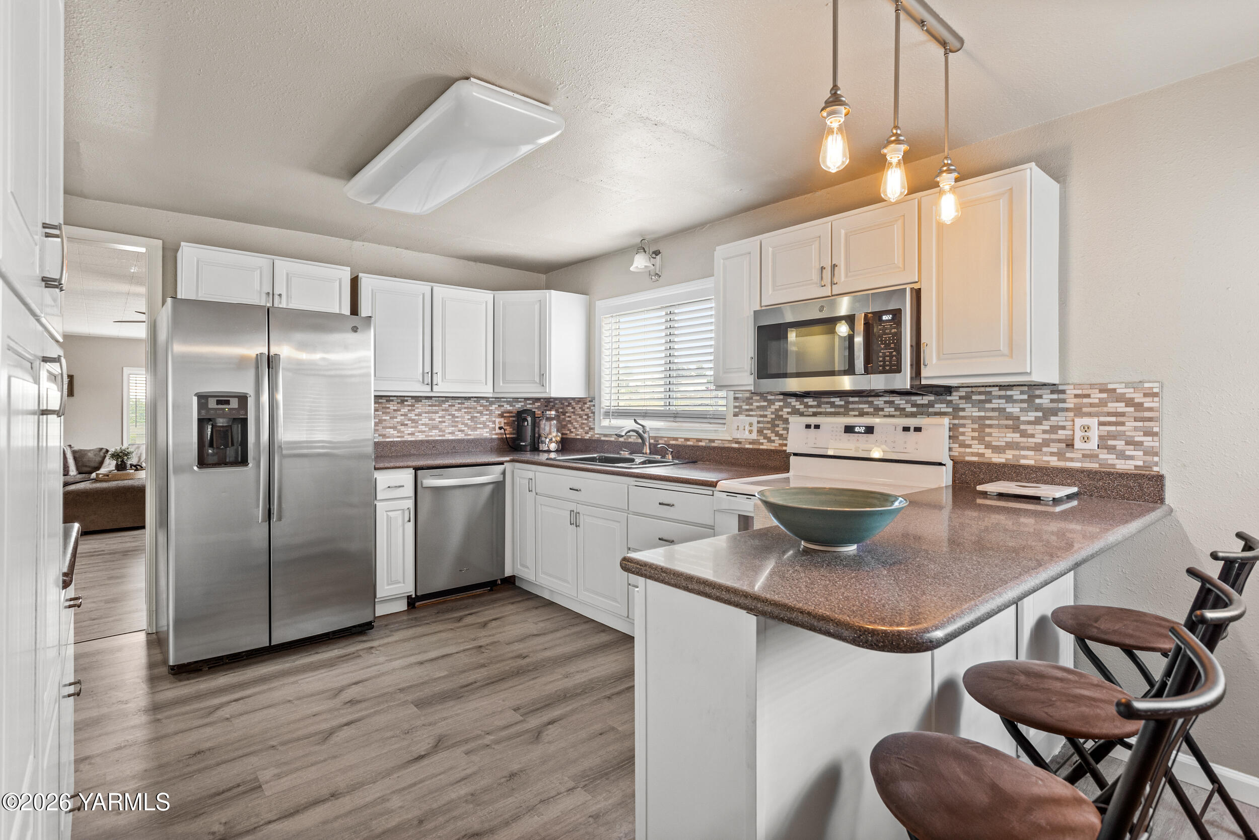 2121 Pleasant Hill Road Selah, WA 98942 - Photo 14 of 38 a kitchen with stainless steel appliances granite countertop a refrigerator a stove a sink dishwasher a dining table and chairs with wooden floor