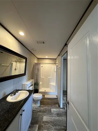a bathroom with a granite countertop sink a toilet a mirror and shower