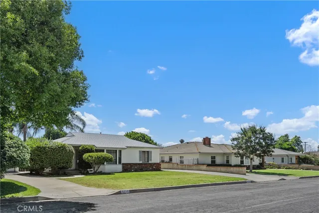 a front view of a house with a big yard and potted plants