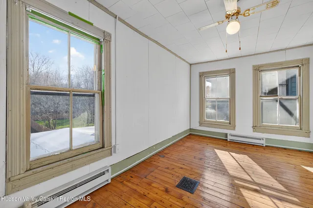 a view of an empty room with a window and wooden floor