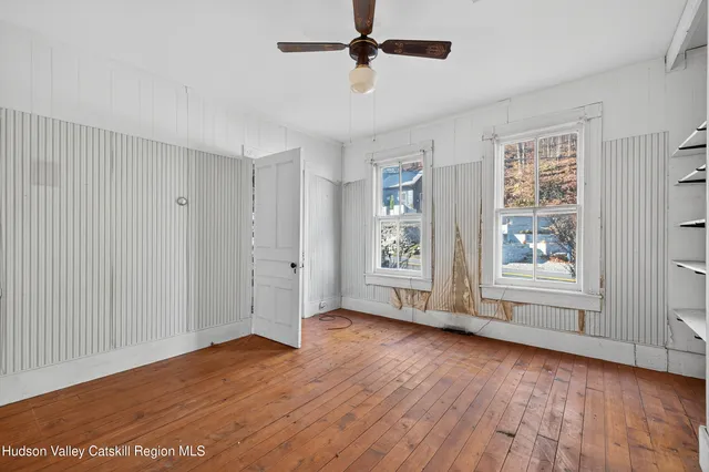 a view of an empty room with wooden floor and a window