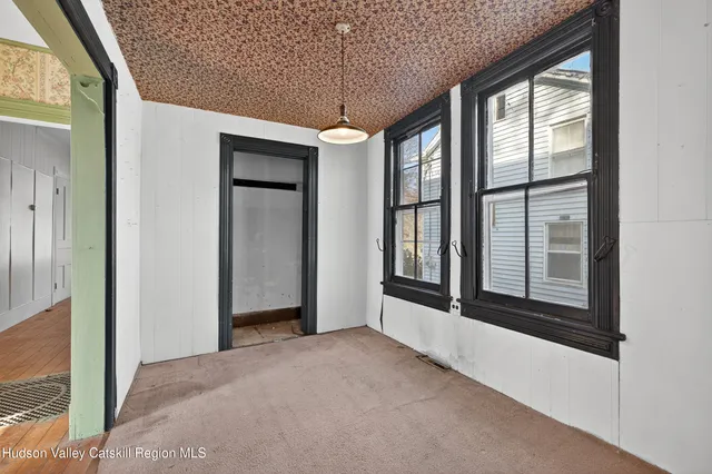 a view of an empty room with a window and chandelier fan