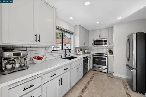 a kitchen with refrigerator a sink a window and white cabinets