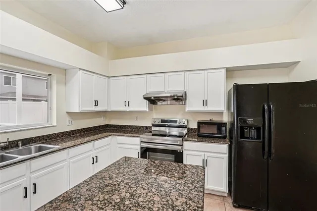 a kitchen with granite countertop a refrigerator sink and stove