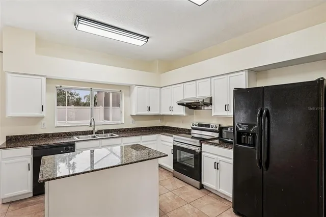 a kitchen with stainless steel appliances granite countertop a stove a refrigerator and a sink