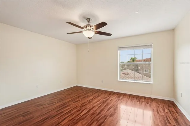 a view of empty room with wooden floor and fan