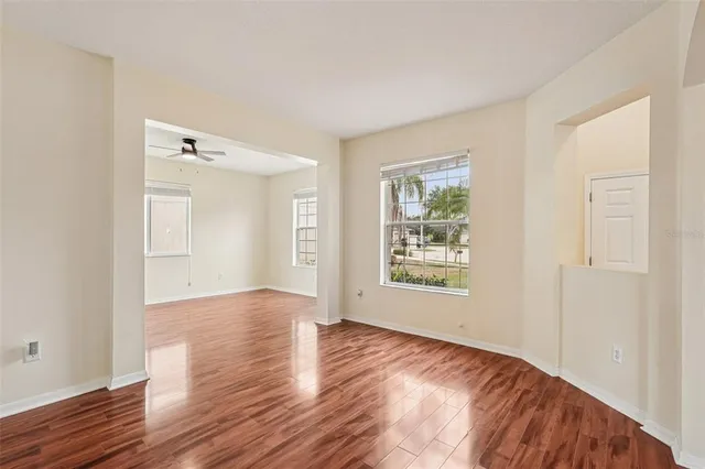 a view of an empty room with wooden floor and a window