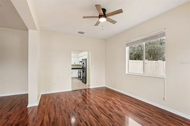 a view of empty room with wooden floor and fan