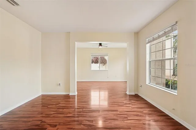 a view of an empty room with wooden floor and a window
