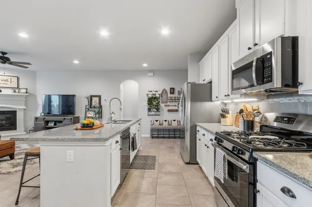 a kitchen with stainless steel appliances granite countertop a stove a sink a microwave a refrigerator and cabinets