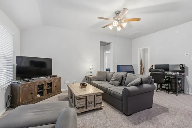 a living room with furniture and a ceiling fan