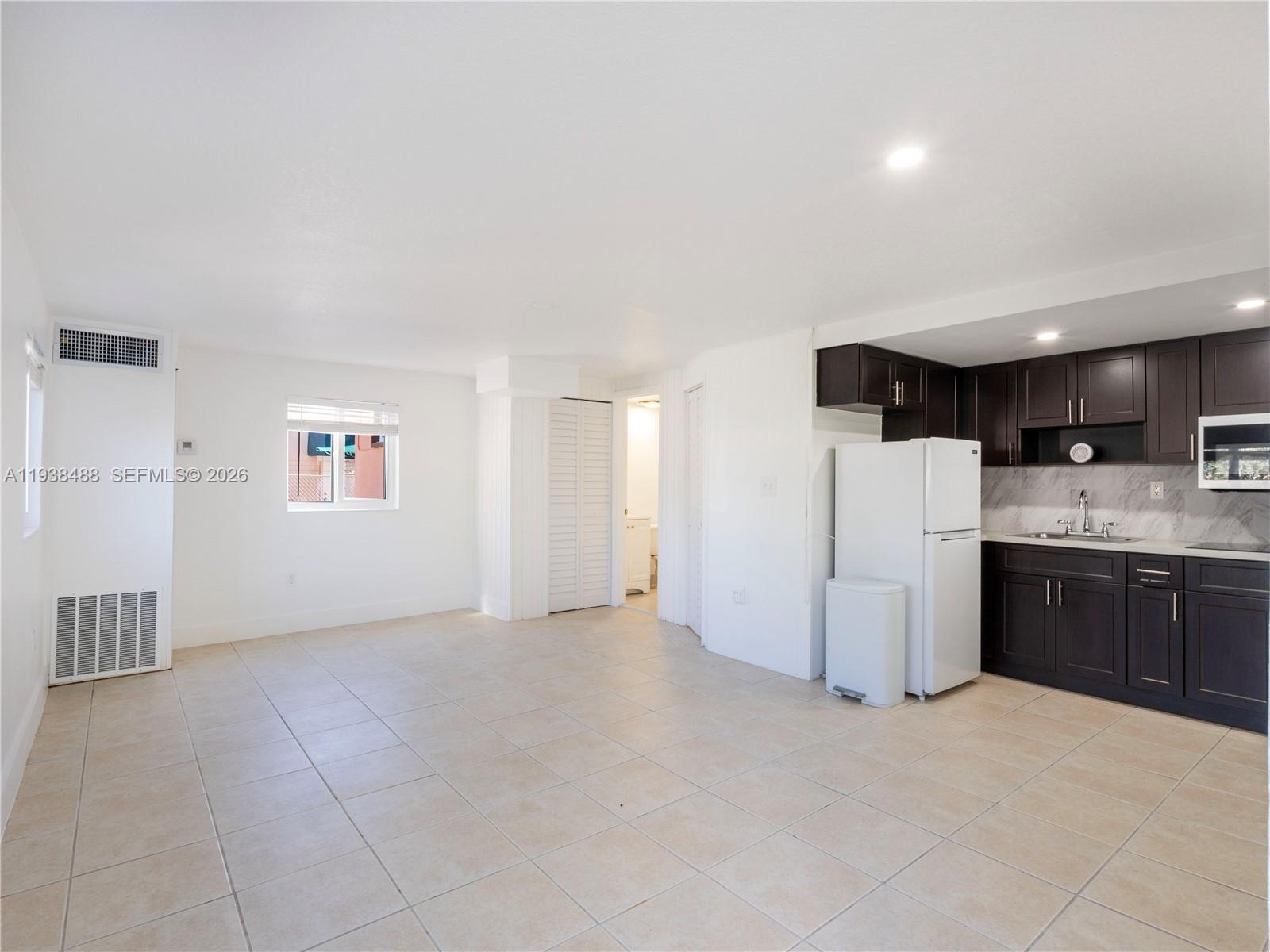 3360 Southwest 6th Street, Unit BOTTOM Miami, FL 33135 - Photo 5 of 17 a view of a kitchen with a sink and dishwasher a refrigerator with white cabinets