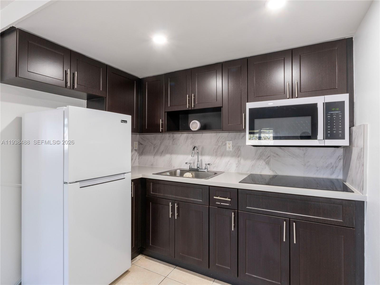 3360 Southwest 6th Street, Unit BOTTOM Miami, FL 33135 - Photo 8 of 17 a kitchen with stainless steel appliances granite countertop a refrigerator and a sink