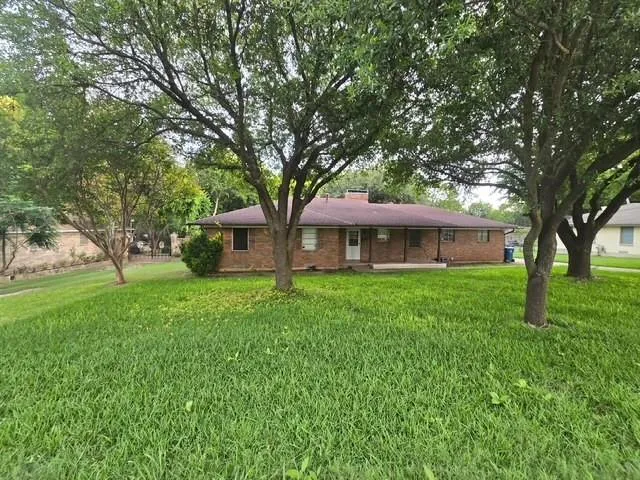 a front view of a house with a garden and trees