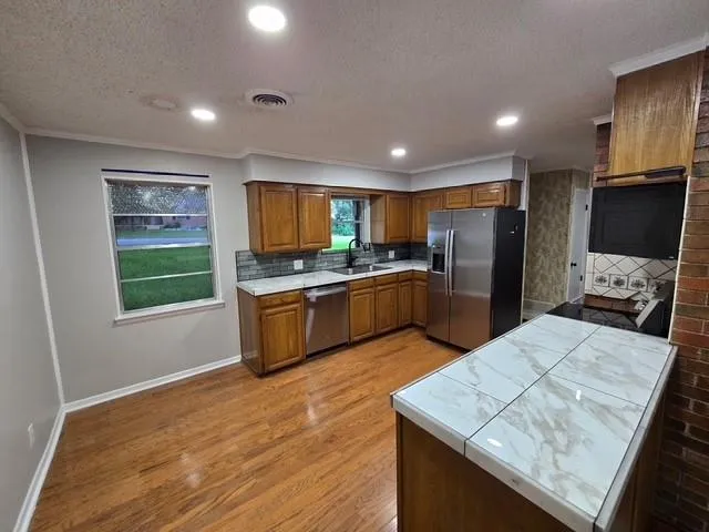 a kitchen with stainless steel appliances wooden floors and wooden cabinets
