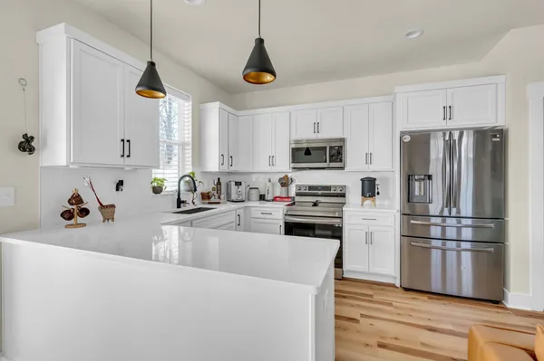 a kitchen with stainless steel appliances granite countertop a refrigerator a stove a sink and white cabinets
