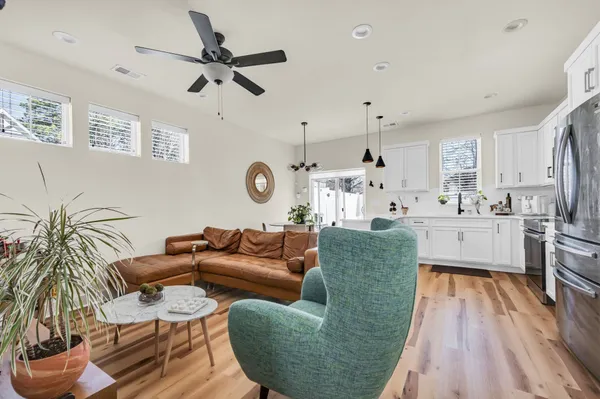 a living room with furniture kitchen view and a chandelier
