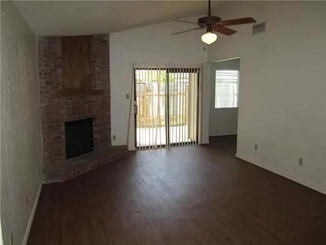 an empty room with wooden floor fireplace and windows