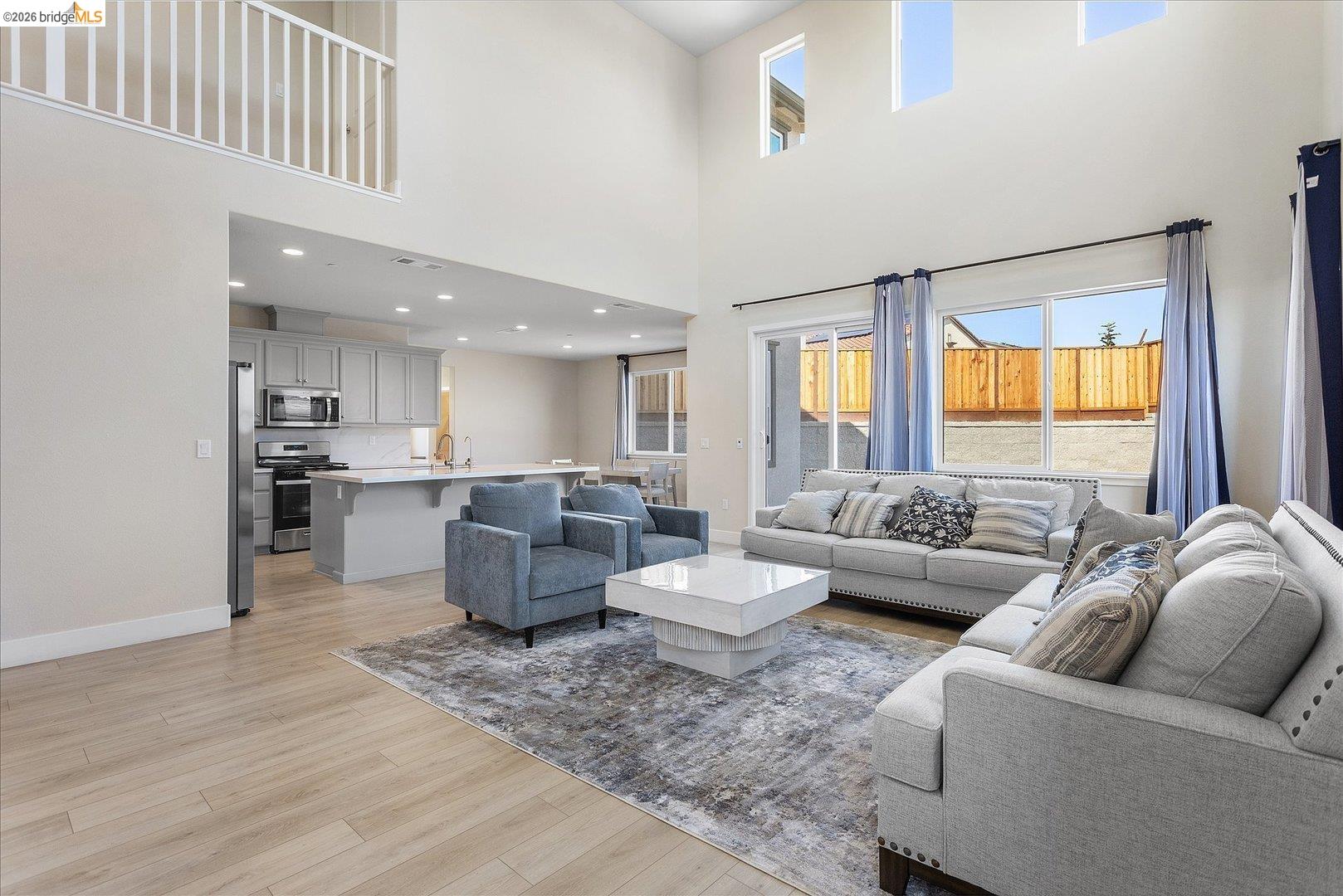 5601 Ridgepoint Way Antioch, CA 94531 - Photo 9 of 59 Open-concept living space featuring high ceilings, wood-finish flooring, a contemporary kitchen with stainless steel appliances, and a sliding glass door to the exterior