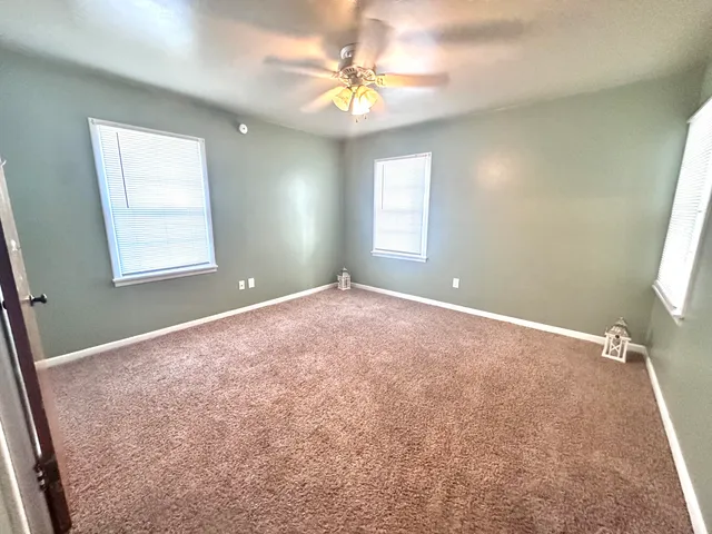 a view of a big room with windows and chandelier fan