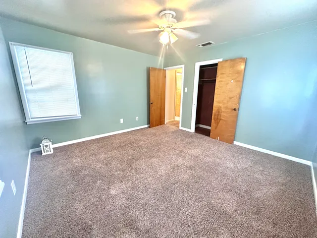 a view of a big room with windows and chandelier fan